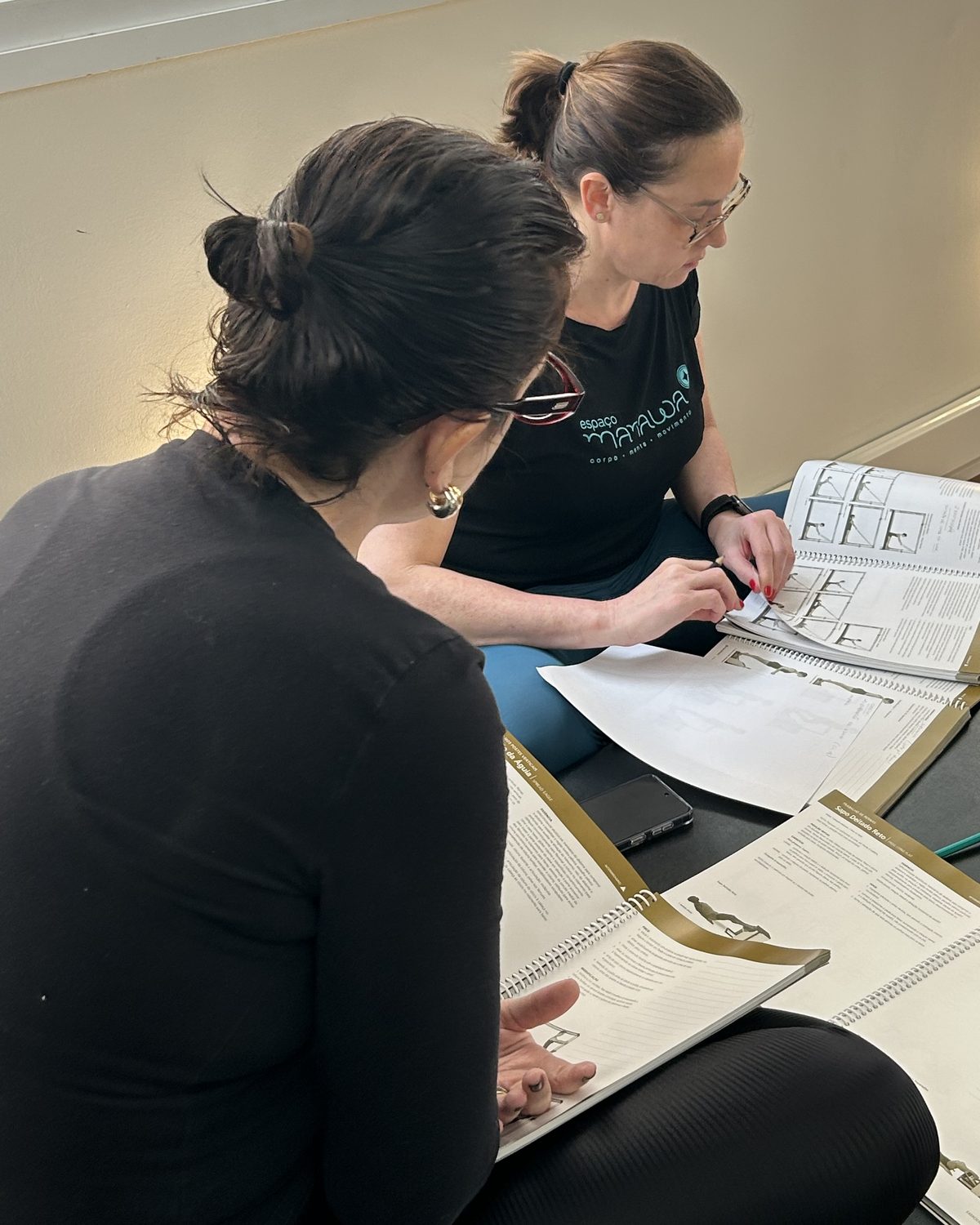 Alunas do Espaço Manawa estudando o material didático STOTT PILATES®